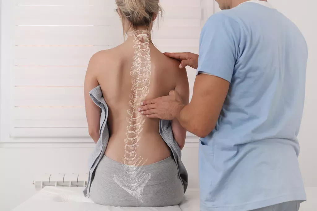 Chiropractor touching spine of woman patient. Illustration of spine drawn over the woman's back.